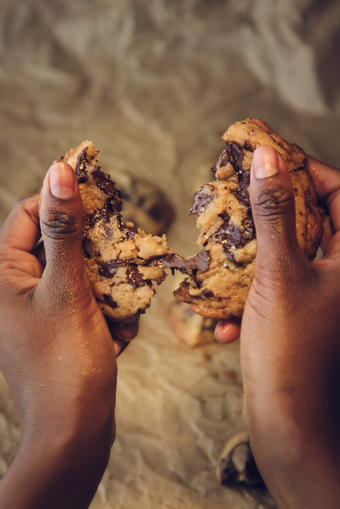 woman pulling chocolate chip cookies apart